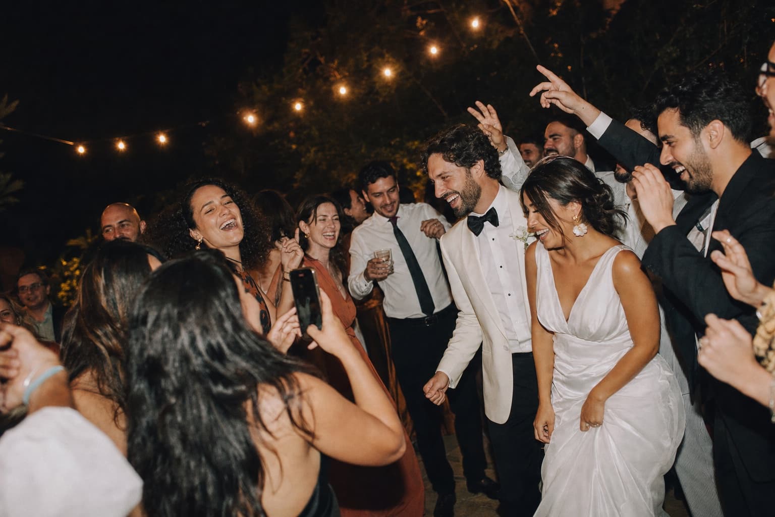 Friends and a newly married couple laughing together on a reception dance floor