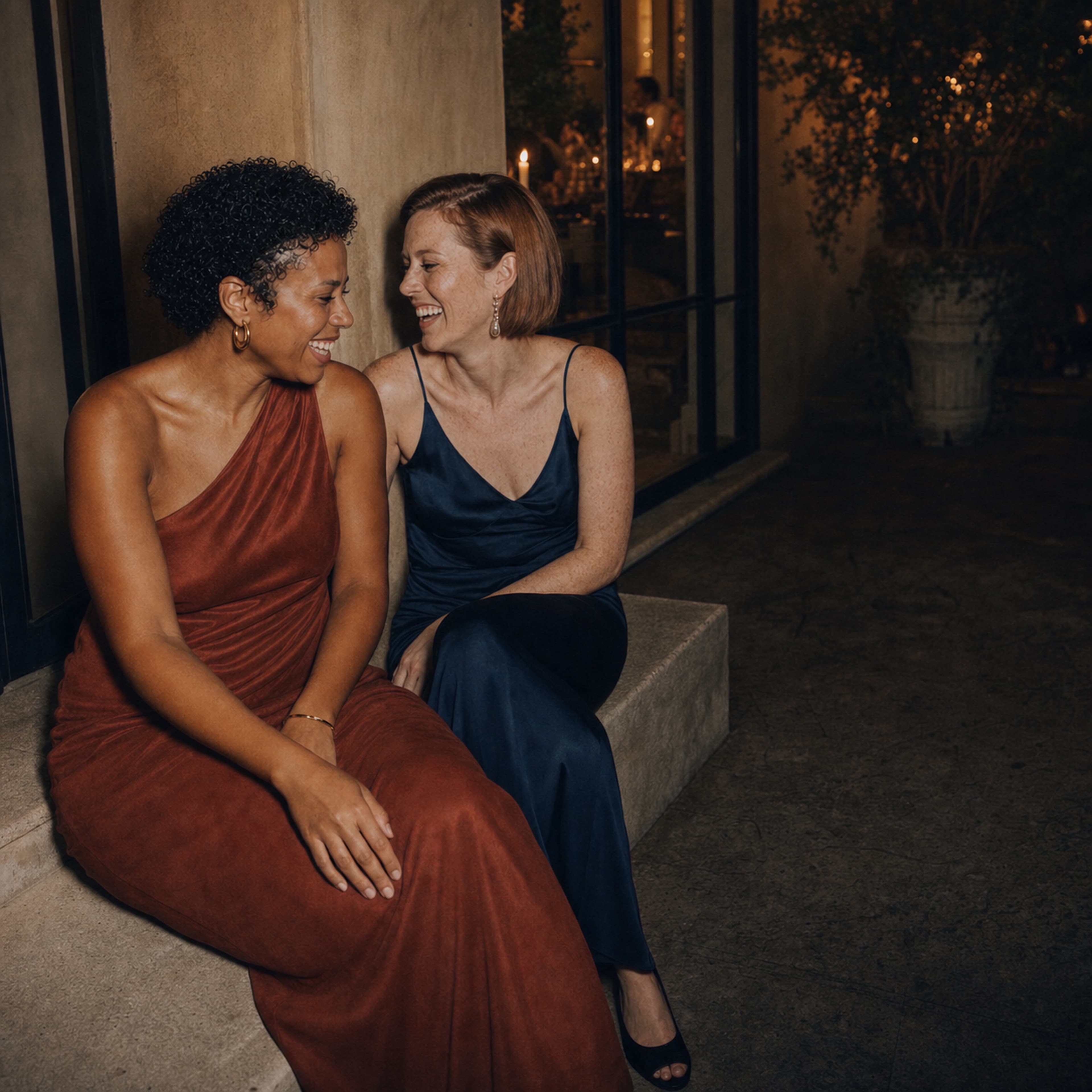 Two wedding guests laughing together on the steps